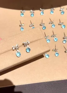 Macro detail view of elegant silver bow-knot earrings with sea blue zircon drop stones