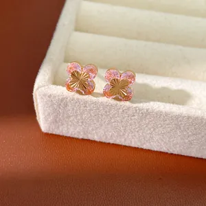 Detalle de cerca de pendientes de botón de flor con circonitas rosas y acabado dorado.