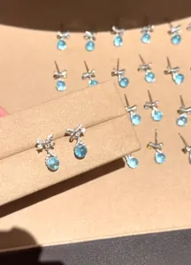 Close-up of elegant silver bow stud earrings with light blue round faceted zircon
