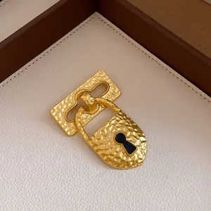 Close-up of vintage hammered gold padlock brooch with black enamel keyhole detail