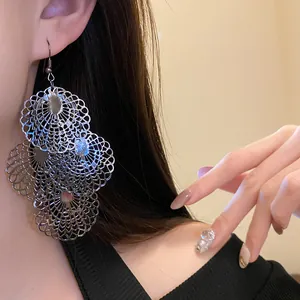 Close-up detail view of metallic hollowed-out lace earrings on a model for a stylish look