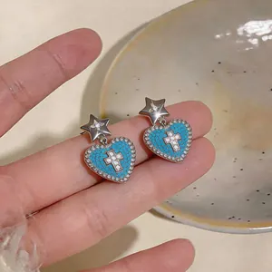 Dettaglio orecchini a cuore in zircone blu con motivo a croce e perno a stella
