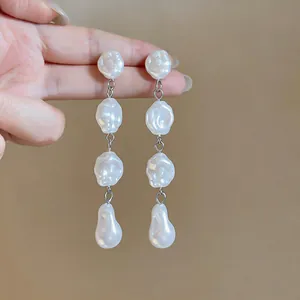Dettaglio di orecchini lunghi con nappe di perle barocche irregolari e aghi in argento puro