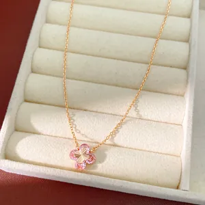 Detalle de un collar de oro rosa con un colgante de flor de circón rosa en un estuche.