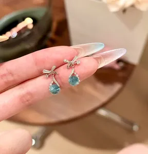 Close-up of elegant bow earrings with blue water drop zircon pendant