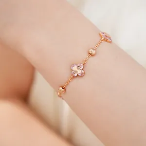 Primer plano detallado de una elegante pulsera de oro rosa con flores de circón rosa en la muñeca