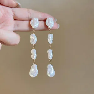 Dettaglio di orecchini a pendente con quattro livelli di perle barocche bianche irregolari