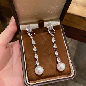 Elegant zircon teardrop tassel clip-on earrings with pearls in a brown jewelry box.