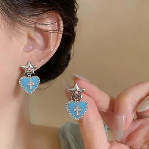 Dettaglio degli orecchini in argento con cuori blu e croce in zircone scintillante