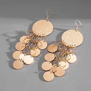 Detailed view of golden metallic drop earrings with hammered finish and sequin tassels.