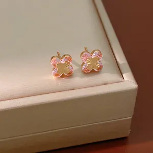 Detalle de pendientes de flor con circonitas rosas en un joyero elegante color champán