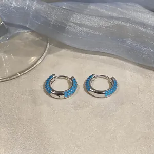 Vista dettagliata di orecchini a cerchio in argento con pietre di zircone blu e tessuto