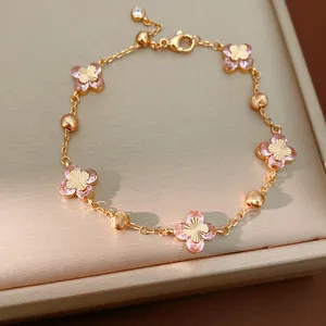 Vista detallada de una pulsera de oro con flores de circón rosa y centros de sol.