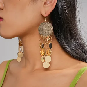 Detailed view of luxury gold metal dangle earrings featuring glittering discs and sequins