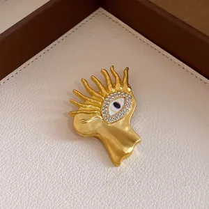 Close-up of a surrealist gold eye brooch featuring radiant flame-like rays and zircons