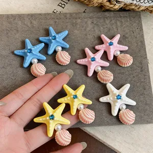 Close-up macro view of colorful starfish hair clips with rhinestones, pearls and shells.