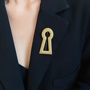 Detail shot of a vintage gold keyhole brooch encrusted with sparkling zircons on a black blazer.