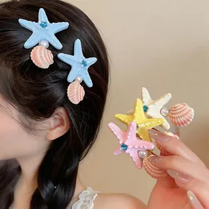 Detailed view of starfish and shell hair clips with pearls and rhinestones on hair and in hand