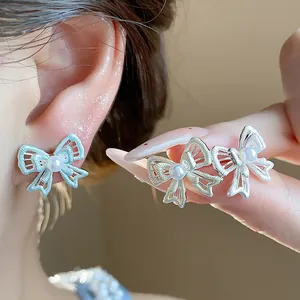 Close-up of hollow bow earrings with pearls for a sweet aesthetic.