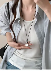 Detail view of a minimalist matte silver teardrop pendant with adjustable black cord.
