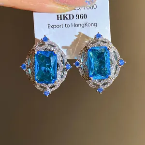 Macro view of luxury vintage style earrings featuring square blue zircon stones and pavé crystals.