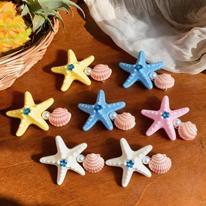Detailed macro view of ocean-themed starfish hair clips with faux pearls and blue rhinestones