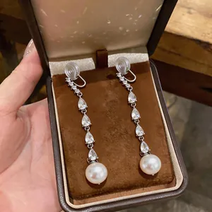 Close-up of elegant teardrop zircon tassel clip-on earrings with round white pearls