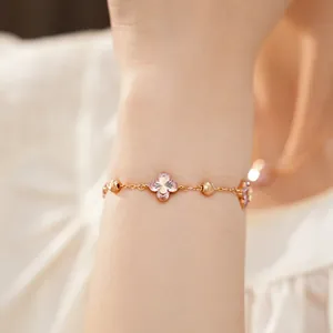 Detalle de elegante pulsera de oro rosa con flores de circón rosa en la muñeca.
