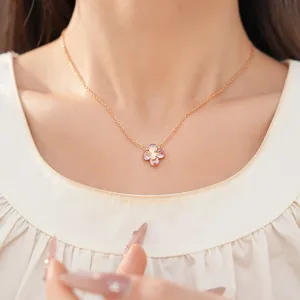 Primer plano de un elegante collar con colgante de flor de circón rosa en el cuello de la modelo.