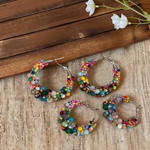 Detailed view of colorful dopamine-style beaded hoop earrings on a rustic background.