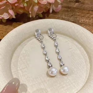 Detailed view of zircon teardrop tassel earrings with round pearls and clip-on back