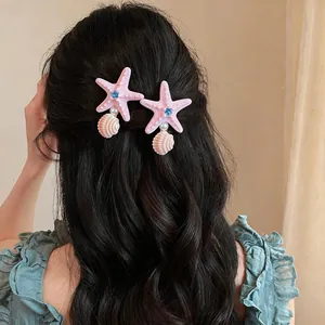 Pink starfish hair clips with pearls and shells on dark wavy hair for beach vacation
