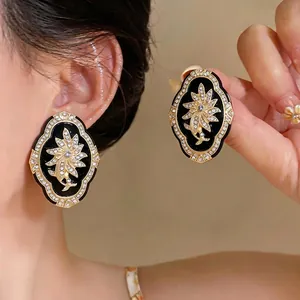 Vintage palace-style black oval earrings with crystal flower motif shown on model ear