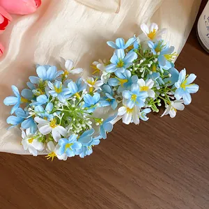 Close-up detail of fresh blue and white fabric flower duckbill hair clips on soft silk