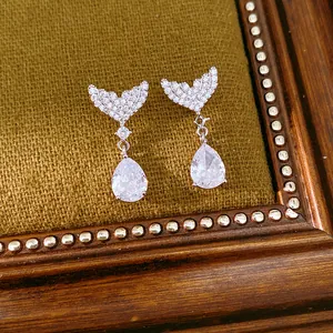 Detailed view of silver needle earrings featuring zircon fishtail and teardrop pendant