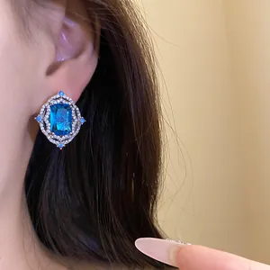Macro view of a luxury vintage blue gemstone earring with diamond halo on an ear