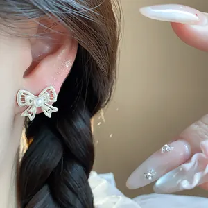 Detailed view of an elegant hollow gold bow stud earring with a white pearl center