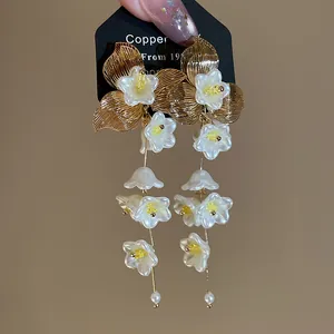 Elegant white floral tassel earrings featuring gold metal accents and pearl drop tips.