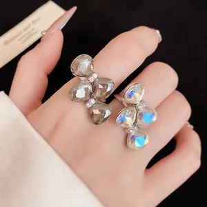 Detail view of rhinestone bow-tie open rings in grey and iridescent stones on hand