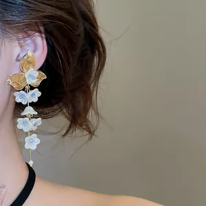 Close-up detail showing elegant French-style white flower tassel pearl earrings on a model