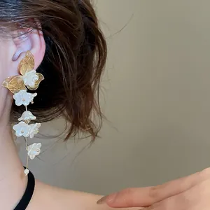 Close-up of elegant French floral tassel earrings with pearl drops on an Asian model.
