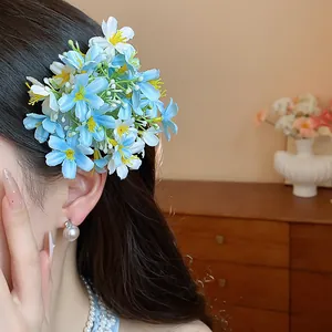 Exquisite blue and white fabric flower hair clip shown on dark hair in detail view