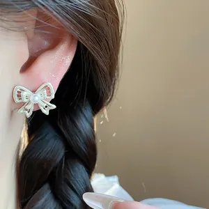 Detailed view of an elegant hollow bow stud earring featuring a central pearl accent