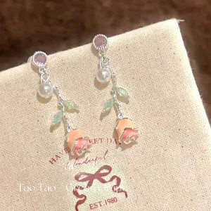 Macro view of detailed enameled rose earrings featuring zircon studs and pearls