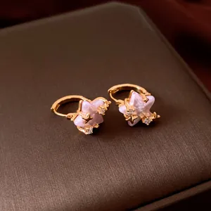 Detail of gold star hoop earrings with pink pearl centers and zircon accents