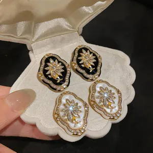 Detail view of vintage court-style floral stud earrings displayed in a white shell gift box.