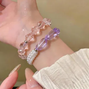 Dettaglio di eleganti braccialetti di perle viola e rosa con dettagli in perle.