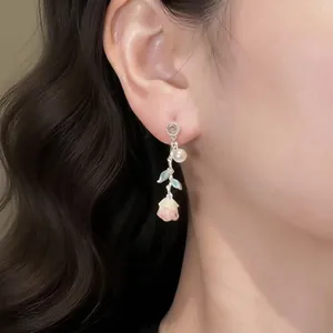 Close-up of elegant silver needle stud earrings with pink rose, zircon and pearl detail