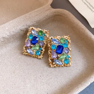 Primo piano di orecchini vintage rettangolari dorati con vivaci strass di vari colori brillanti