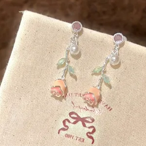 Macro view of elegant rose flower drop earrings with pearls and pink zircon accents